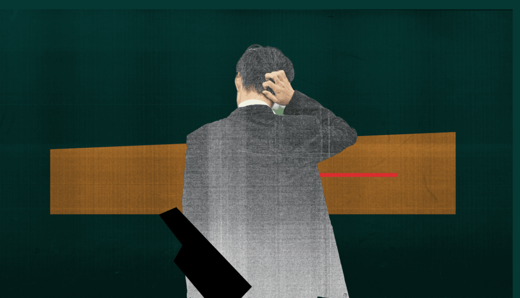 Male-presenting person in suit, scratching head.